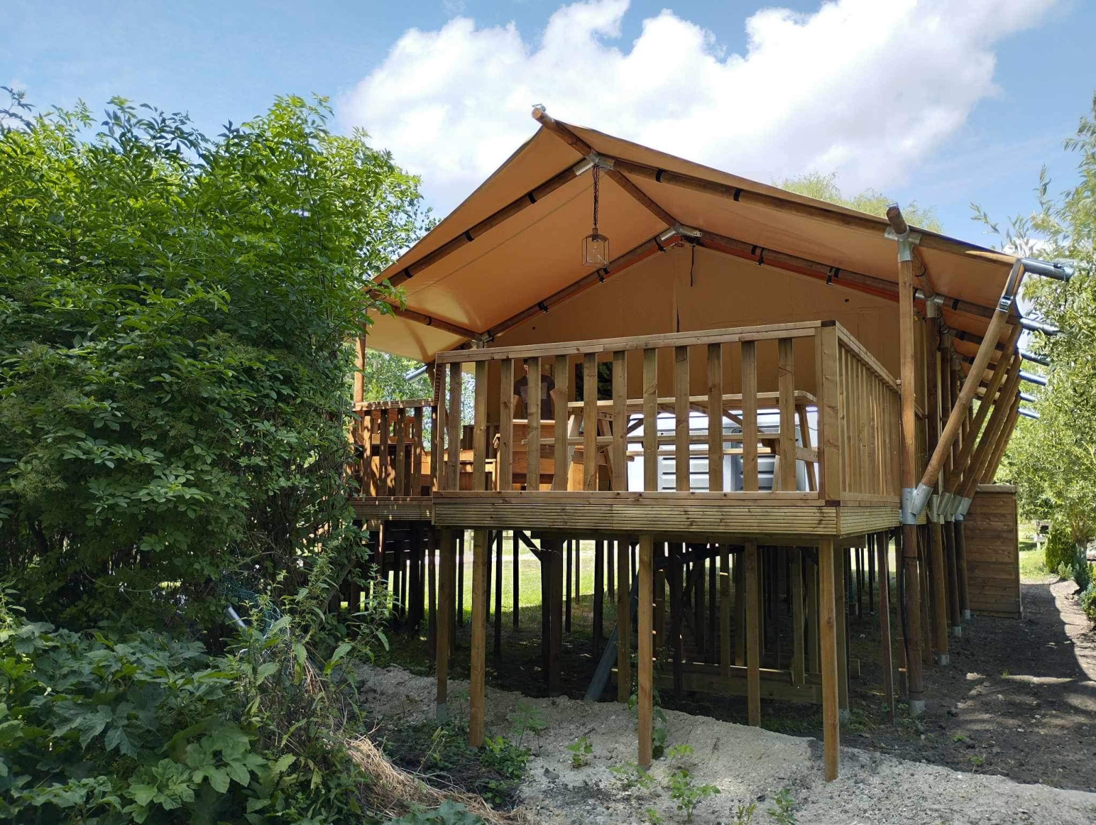 Safari Tent XXL met buitenjacuzzi bij Flower Camping de la Trye in Frankrijk, verhoogd op palen.
