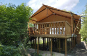 Safari Tent XXL met buitenjacuzzi bij Flower Camping de la Trye in Frankrijk, verhoogd op palen.