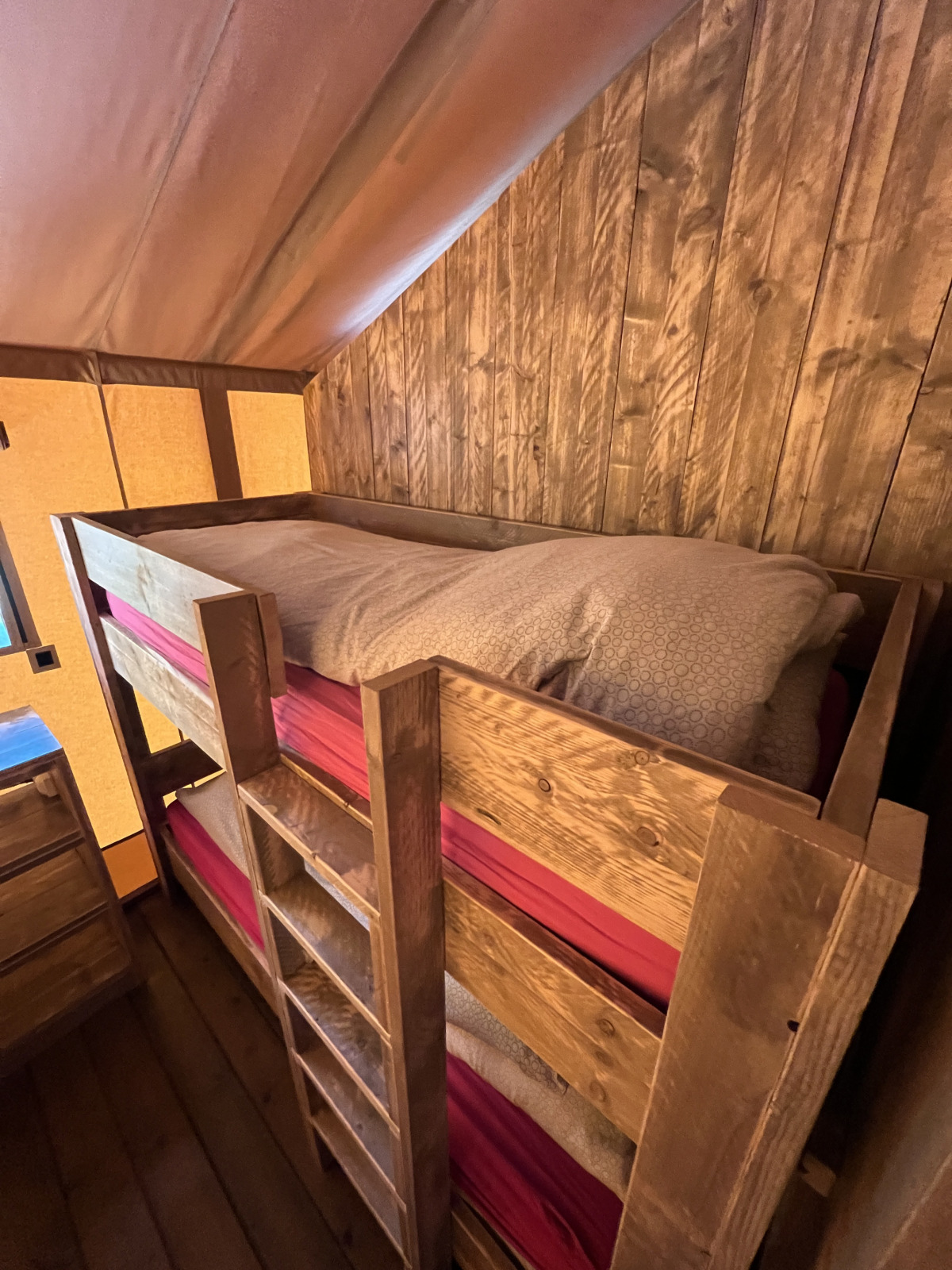 Houten stapelbedden in een safaritent bij Flower Camping de la Trye in Frankrijk, met rustiek interieur.