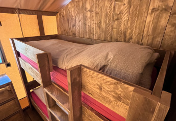 Houten stapelbedden in een safaritent bij Flower Camping de la Trye in Frankrijk, rustieke uitstraling.