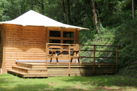Wooden lodge with terrace, picnic table and deck chairs in a forest, Lodge Bali at Moulin de Chaules, France.