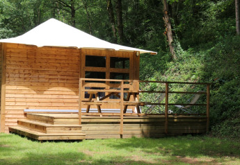 Holzhütte mit Terrasse, Picknicktisch und Liegestuhl im Wald, Lodge Bali, Camping Moulin de Chaules, Frankreich.
