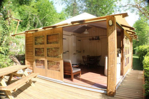 Lodge Bali, struttura in legno con facciata aperta, terrazza e tavolo da picnic immersa nel verde.