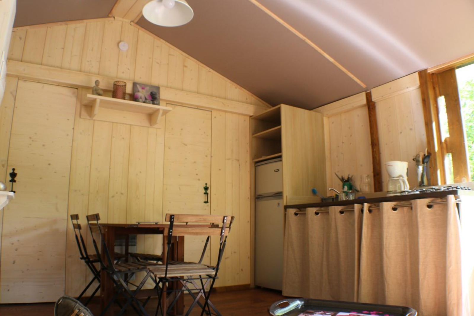 Interieur van Lodge «Bali» op Camping Moulin de Chaules in Frankrijk met eettafel en kitchenette.