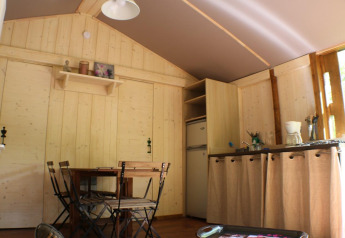 Innenansicht der Lodge «Bali» auf dem Campingplatz Moulin de Chaules in Frankreich mit Essbereich und Küche.