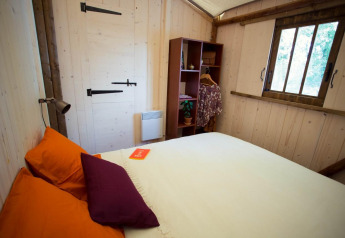 Accogliente camera da letto nella Lodge «Bali» al Campeggio Moulin de Chaules con pareti in legno.