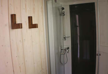 Doccia con porta di vetro e parete in legno con ganci presso Lodge «Bali», Campeggio Moulin de Chaules, Francia.