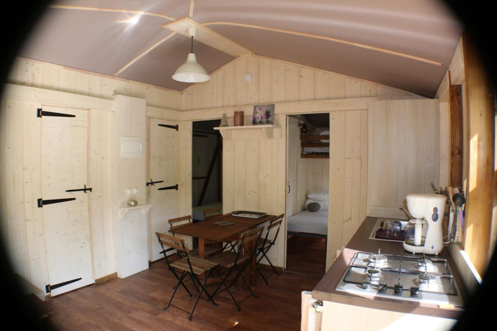 Interieur van Lodge 'Bali' op Camping Moulin de Chaules, met lichte houten muren en eethoek.