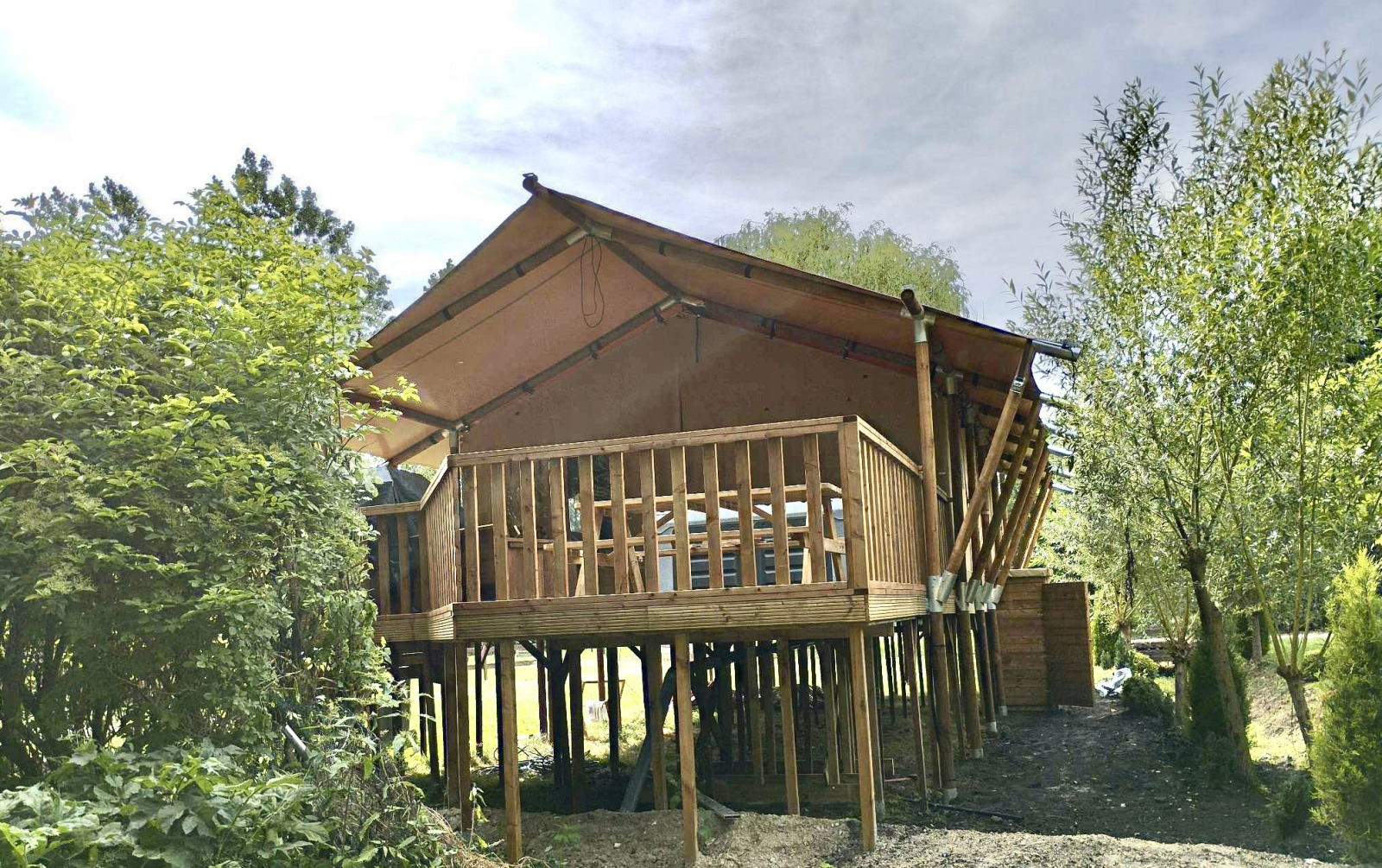 Safari Tent XXL met jacuzzi bij Flower Camping de la Trye in Frankrijk, op houten palen in groene natuur.