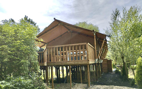 Safari-tent XXL met jacuzzi bij Flower Camping de la Trye in Frankrijk, op palen tussen het groen.