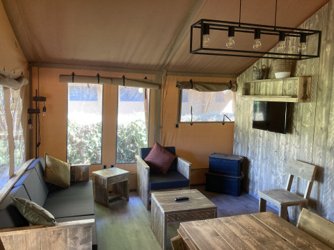 Interieur van de Safari Tent XXL met robuust houten meubilair bij Flower Camping de la Trye in Frankrijk.