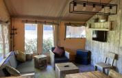 Interieur van de Safari Tent XXL met rustieke houten meubels bij Flower Camping de la Trye in Frankrijk.