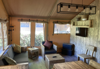 Interieur van de Safari Tent XXL met robuust houten meubilair bij Flower Camping de la Trye in Frankrijk.