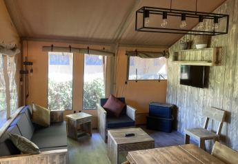 Interieur van de Safari Tent XXL met robuust houten meubilair bij Flower Camping de la Trye in Frankrijk.