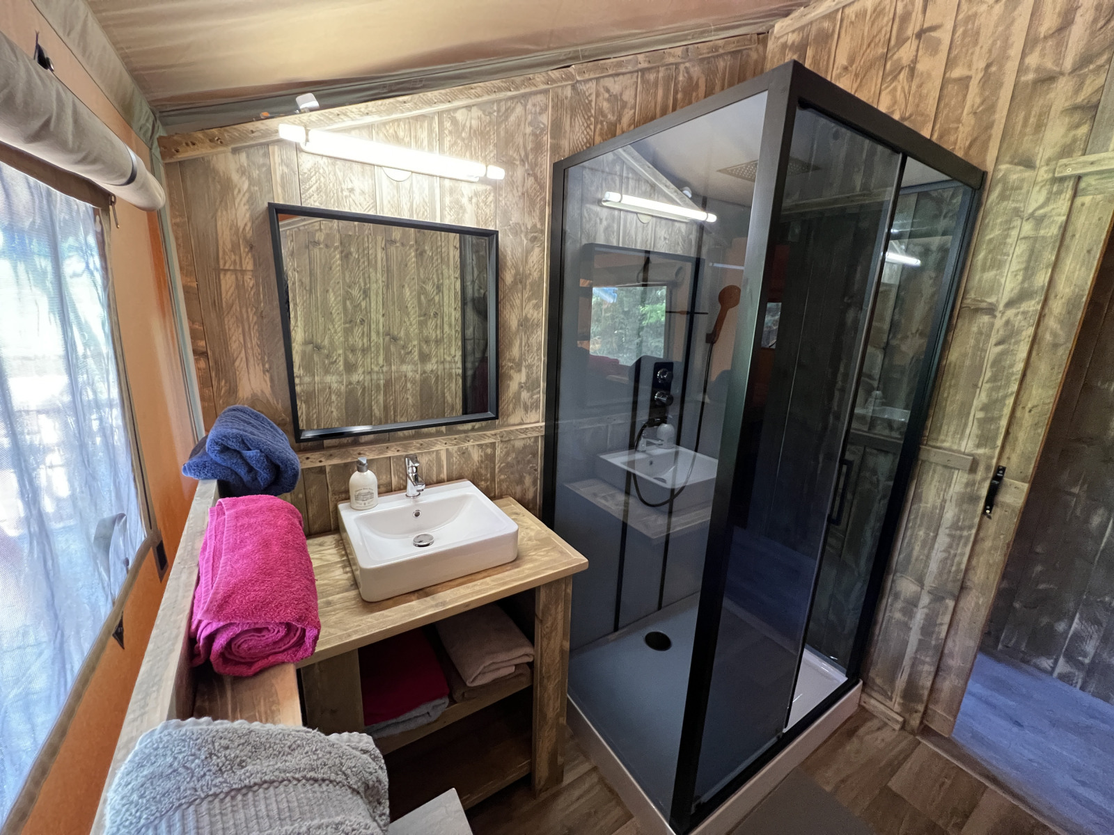 Badkamer in Safari Tent XXL met douche, wastafel en handdoeken bij Flower Camping de la Trye in Frankrijk.