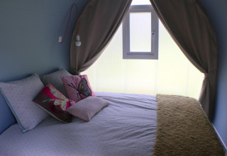 Interior of a CocoSweet safari tent at Campsite Moulin de Chaules, France, featuring a cozy bed and butterfly pillows.