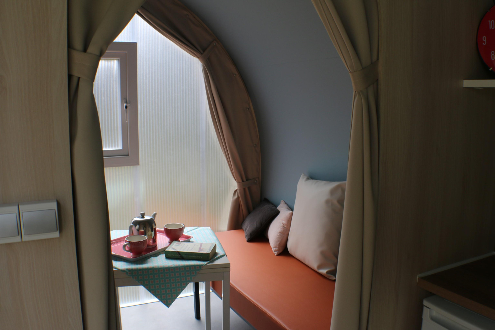 Interieur van een CocoSweet safaritent op Camping Moulin de Chaules, met tafeltje, theepot en oranje bank.