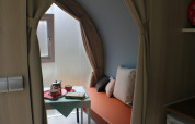 Interno di una tenda safari CocoSweet al campeggio Moulin de Chaules con tavolo, teiera e panca arancione.