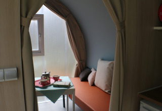 Interior of a CocoSweet safari tent at Campsite Moulin de Chaules, featuring a table, tea set, and orange bench.