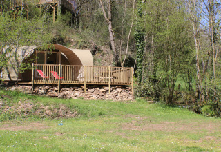CocoSweet safari tent at Campsite Moulin de Chaules, France, featuring a deck with chairs in a wooded setting.