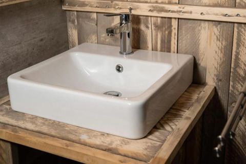Vasque blanche moderne avec robinet chromé dans une salle de bain rustique au Centro Vacanze San Marino glamping.