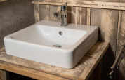 Vasque blanche moderne avec robinet chromé dans une salle de bain rustique au Centro Vacanze San Marino glamping.