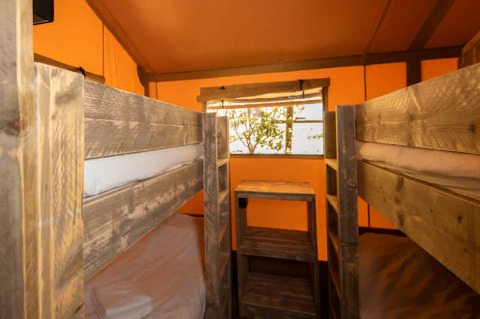 Intérieur d'une tente glamping avec lits superposés en bois au Centro Vacanze San Marino - Safaritenten San Marino.