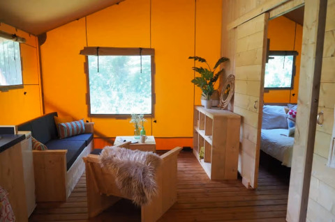 Intérieur d'une tente glamping avec mobilier en bois et décoration chaleureuse au Centro Vacanze San Marino.