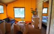 Interno di una tenda glamping con arredi in legno, pareti arancioni e ambiente accogliente a San Marino.