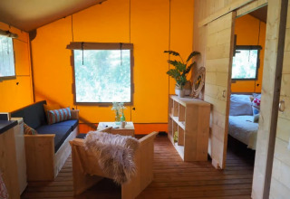 Inde i et glamping telt med lyst træinteriør, farverige vægge og hyggeligt opholdsrum i San Marino.
