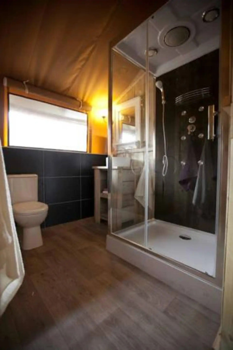 Salle de bain moderne dans une tente safari glamping au Centro Vacanze San Marino avec douche et WC.