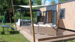 Buitenterras bij Luxe Lodge met lounge, jacuzzi, picknicktafel en groene natuur rondom.