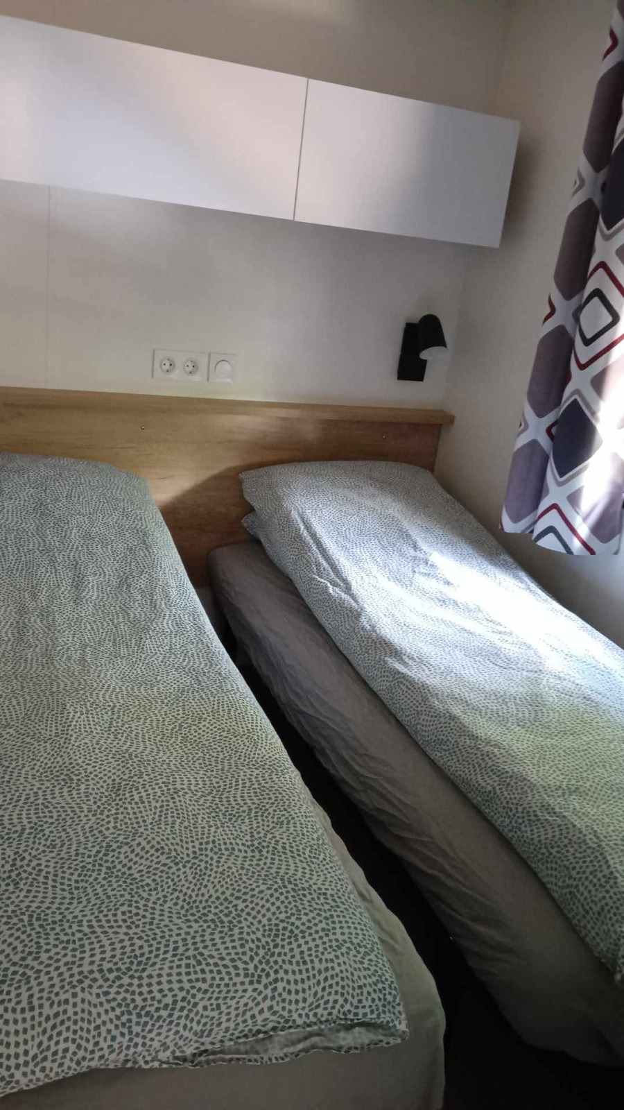 Twee eenpersoonsbedden met dekbedden in een lichte kamer bij Luxe Lodge + jacuzzi, Flower Camping de la Trye.