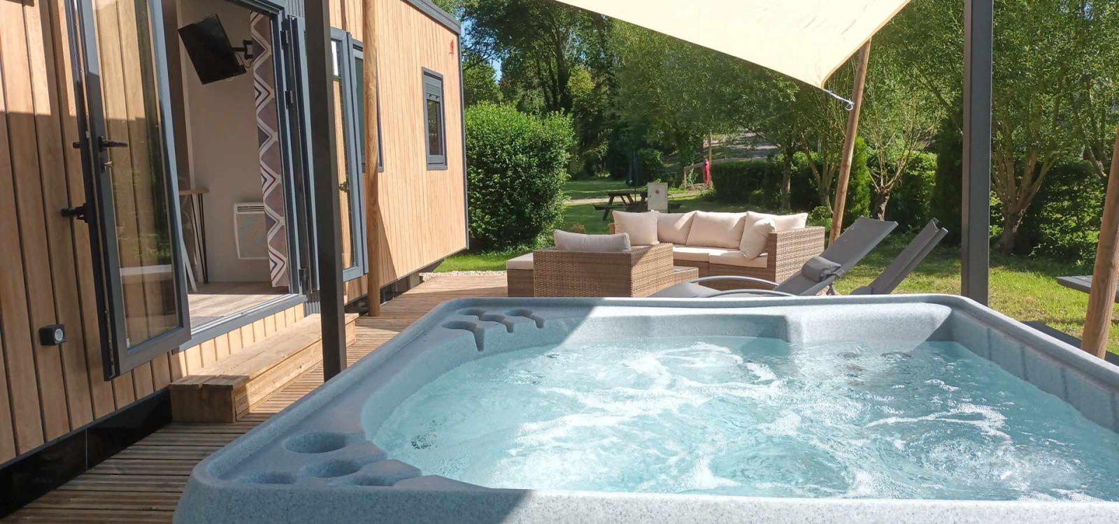 Bubbelbad en terras bij Luxe Lodge op Flower Camping de la Trye in Frankrijk met zithoek.