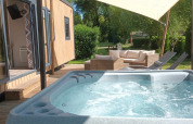Bubbelbad en terras bij Luxe Lodge op Flower Camping de la Trye in Frankrijk met zithoek.
