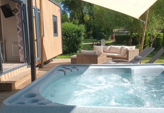 Bubbelbad met terras bij Luxe Lodge op Flower Camping de la Trye in Frankrijk met loungehoek.