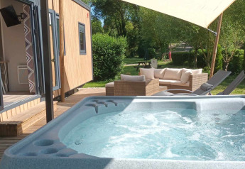 Bubbelbad met terras bij Luxe Lodge op Flower Camping de la Trye in Frankrijk met loungehoek.