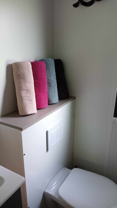 Badkamer bij Luxe Lodge, Flower Camping de la Trye, Frankrijk, met vier gekleurde handdoeken en toilet.