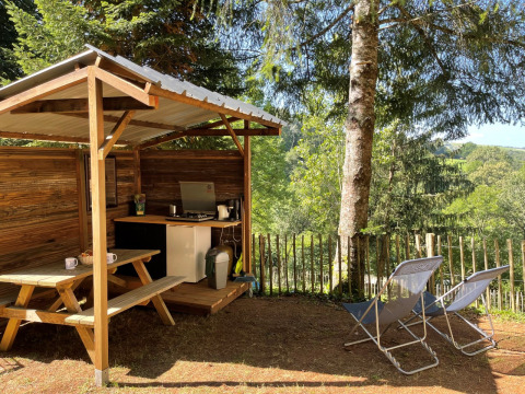Outdoor kitchen and seating area at Emperor Bell Tent, Campsite Moulin de Chaules, surrounded by nature.