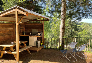 Outdoor kitchen and seating area at Emperor Bell Tent, Campsite Moulin de Chaules, surrounded by nature.