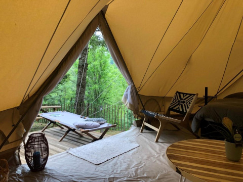 Interior of safari tent 'Emperor Bell Tent' at Campsite Moulin de Chaules in France, offering a view of the trees.