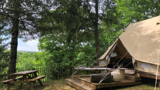 Esperienza safari in una Emperor Bell Tent con terrazza in legno e tavolo da picnic in ambiente boschivo.