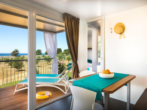 Lichte cabininterieur met eettafel en toegang tot terras met uitzicht op zee in Kroatië.