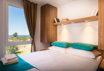 Moderne slaapkamer met tweepersoonsbed, turquoise kussens en zeezicht bij Aminess Maravea Resort, Kroatië.