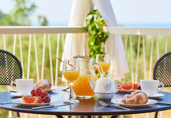 Desayuno al aire libre en un balcón con croissants, zumo, té y fruta en Miramí Family Village, Croacia.