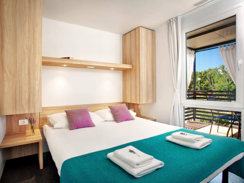 Gezellige slaapkamer in Maravea Family Holiday Home bij Aminess Planet Camping Maravea Resort in Kroatië met balkon.