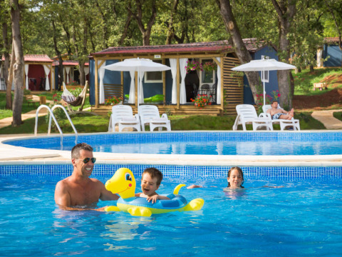Een gezin geniet van het zwembad bij hun hut aan het Maravea Family Holiday Home, Aminess Planet Camping Maravea Resort, Kroatië.