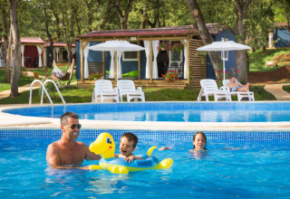 Een gezin geniet van het zwembad bij hun hut aan het Maravea Family Holiday Home, Aminess Planet Camping Maravea Resort, Kroatië.