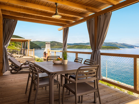 Overdekt terras met eettafel, stoelen en spectaculair zeezicht bij Marina Home Spectacular Seaview, Valamar Camping Marina, Kroatië.