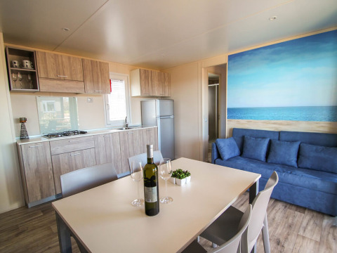 Modern Park Riviera 2-bedroom lodge at Campsite Park Umag, Croatia, featuring a kitchen, dining area and sofa.